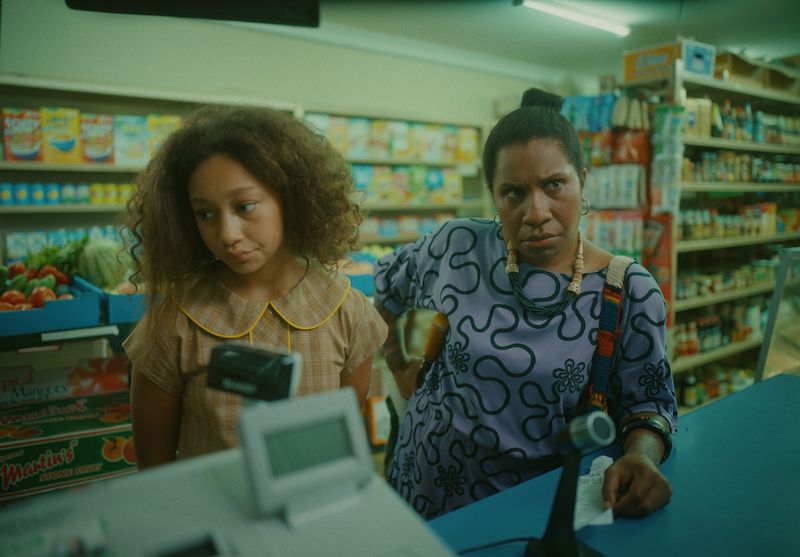 Image shows a Papua New Guinean Mum and daughter standing at a supermarket checkout. Both look unimpressed.